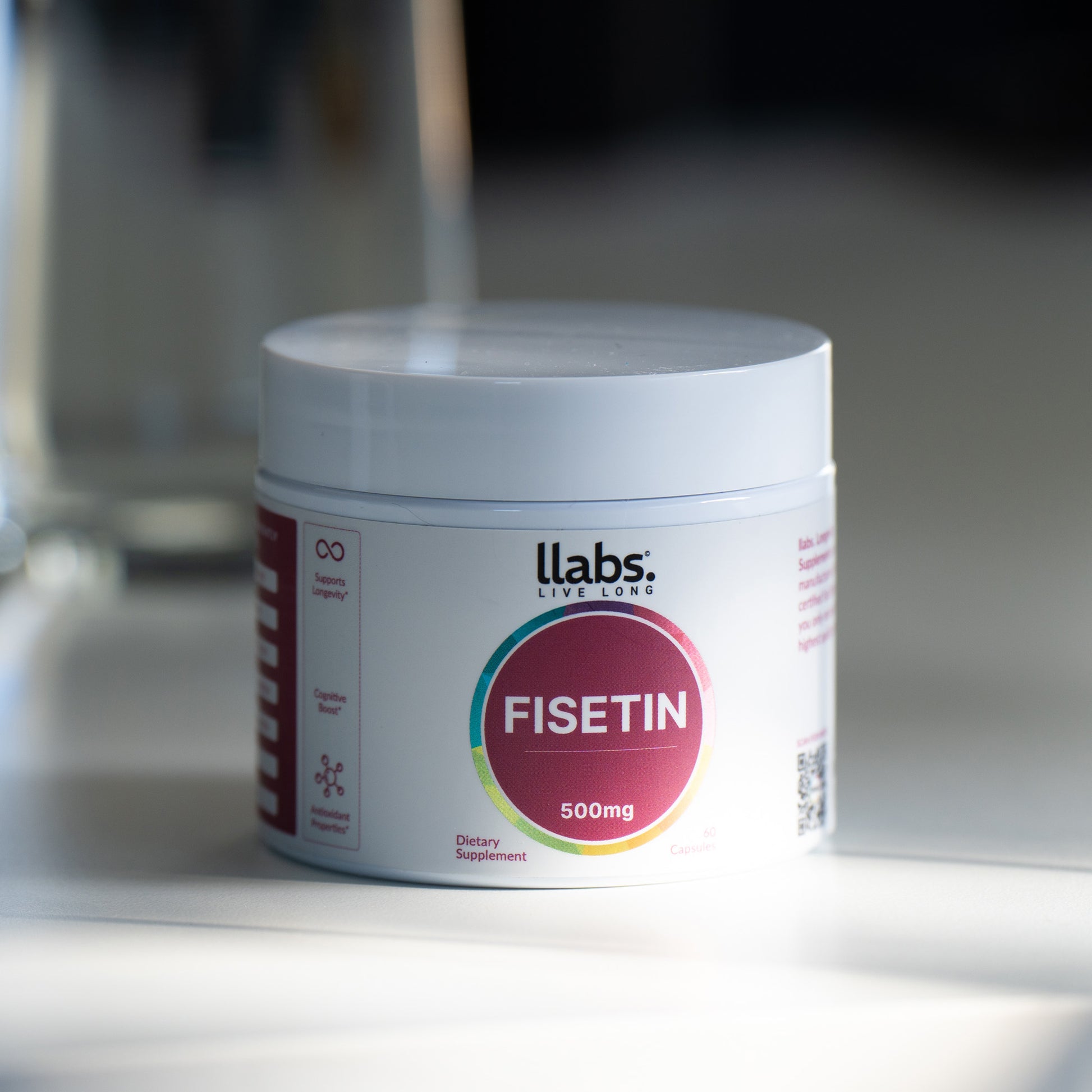 A container of llabs fisetin capsules - 2 months supply with a 500mg label, resting on a surface under natural light.