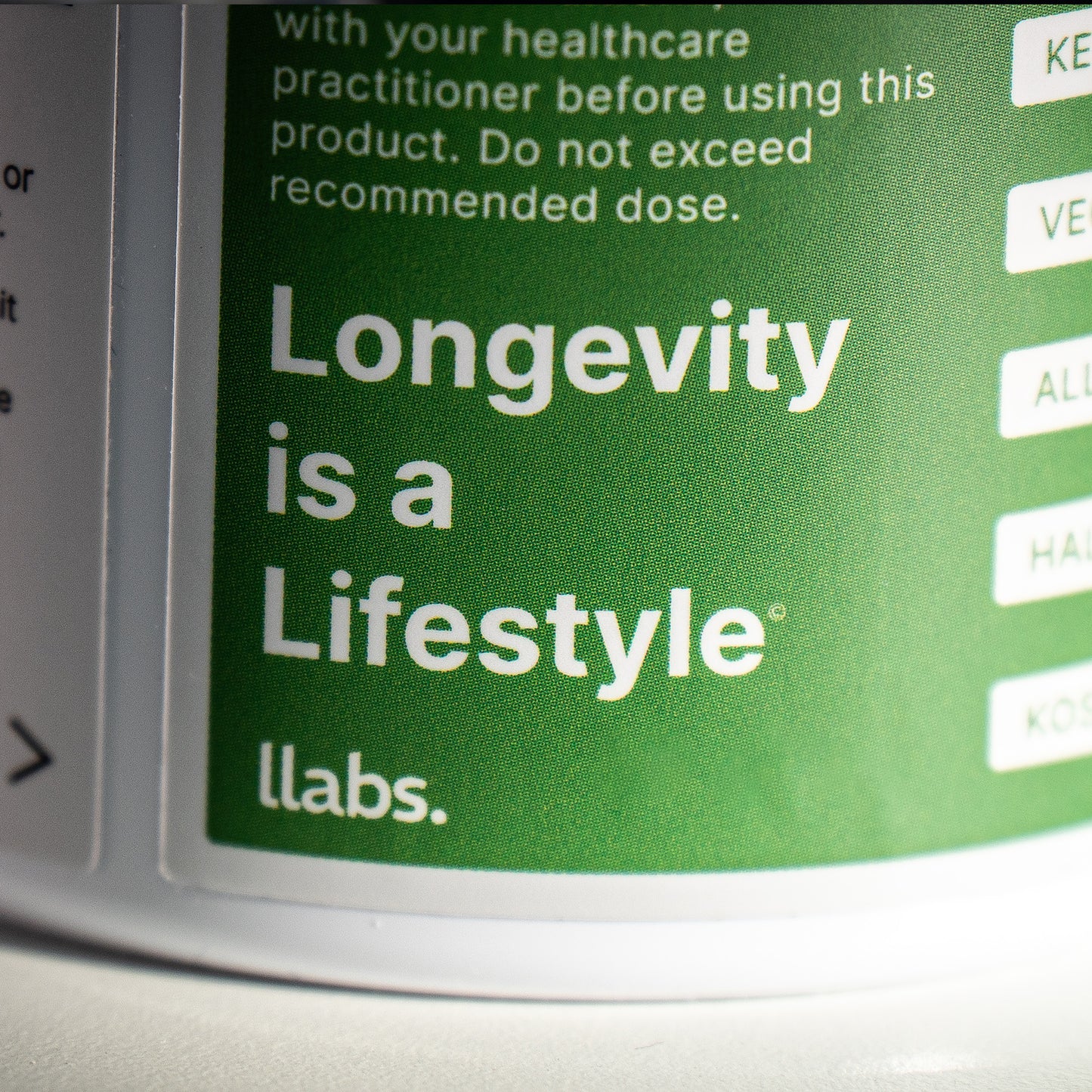 Close-up of a llabs. TMG (Betaine) Capsules bottle with the slogan "longevity is a lifestyle" visible on the label.